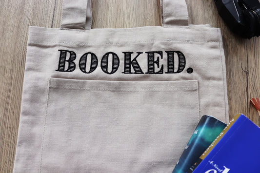 “Booked.” Canvas Tote Bag